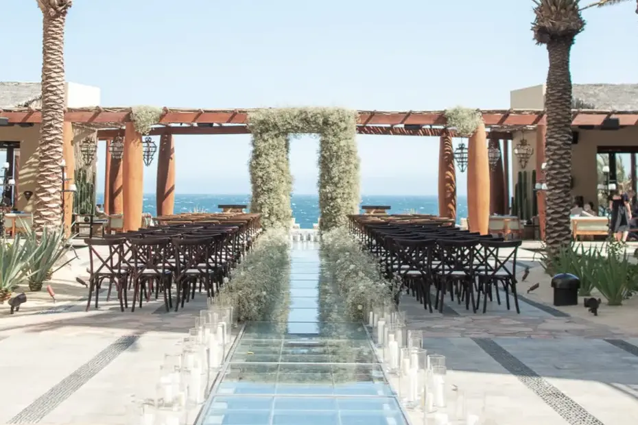 An oceanfront ceremony set with a floral arch above the aisle