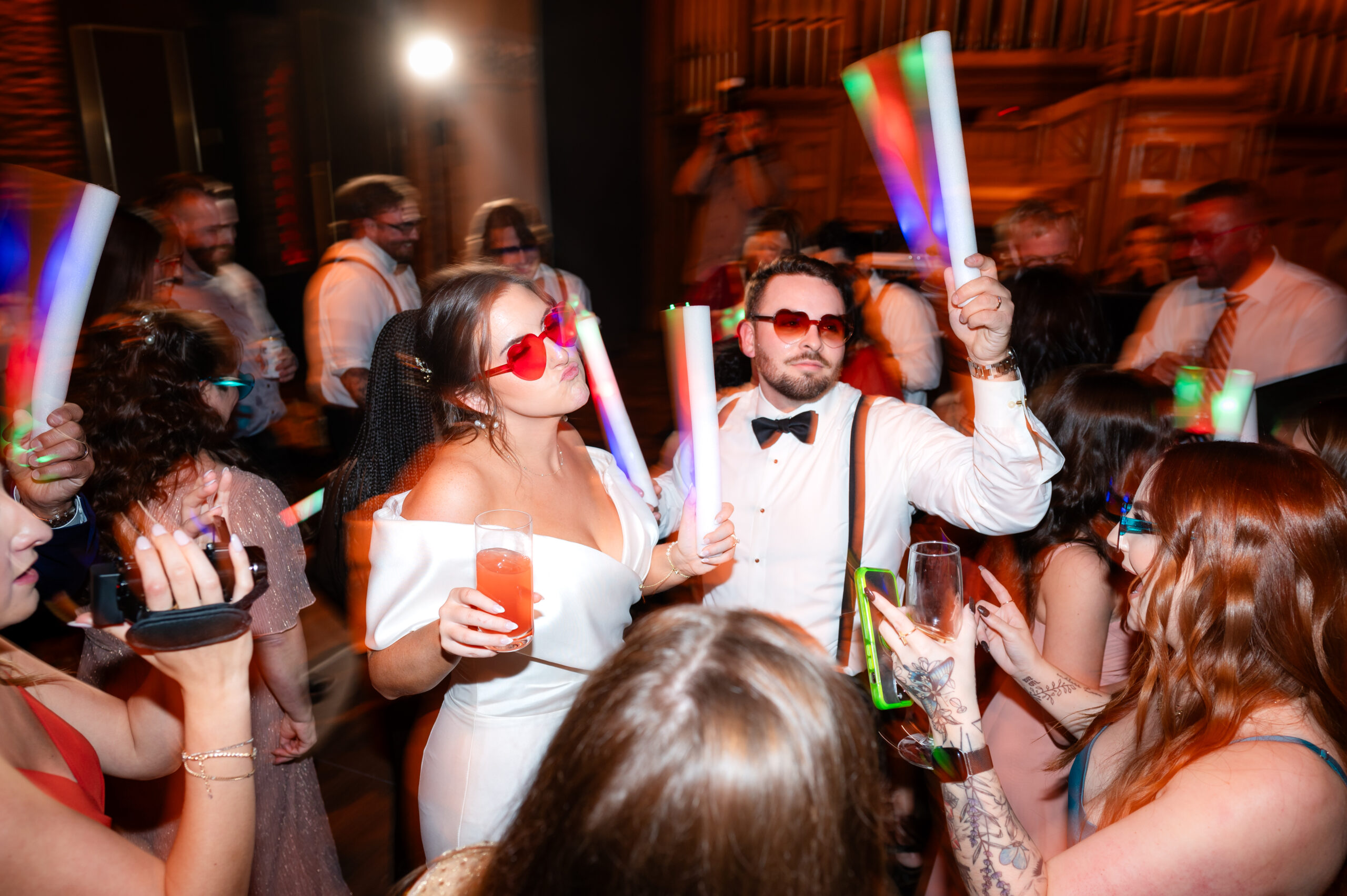 Bride and groom celebrating with guests on a lively wedding dance floor