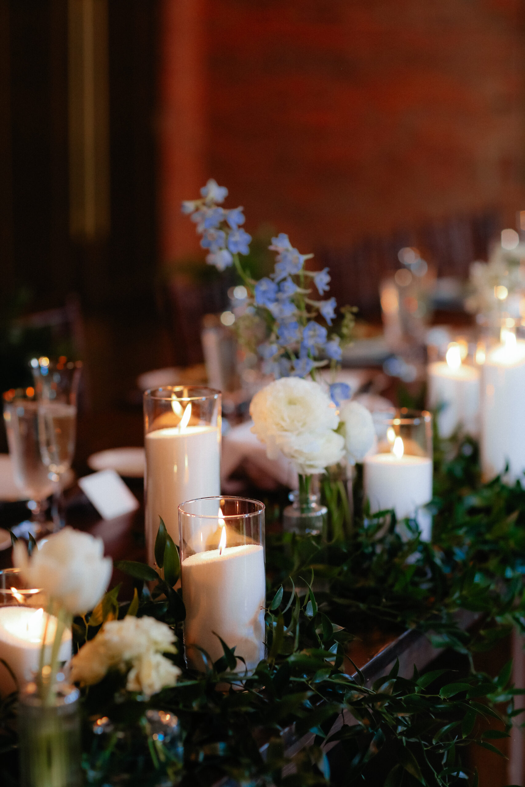 Wedding reception centerpiece of pillar candles and blue and white blooms