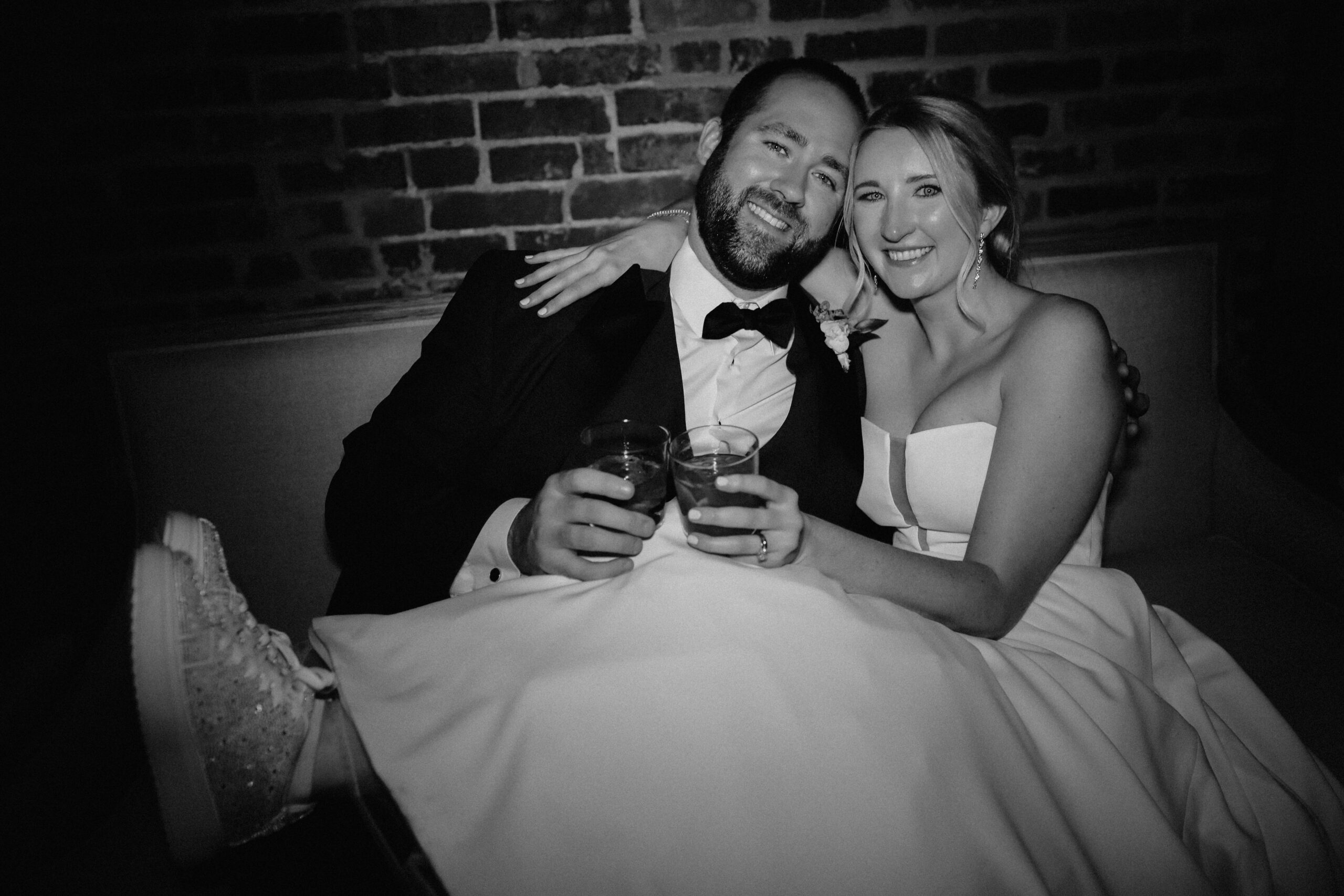 Newlyweds relaxing with drinks on a lounge at their wedding reception