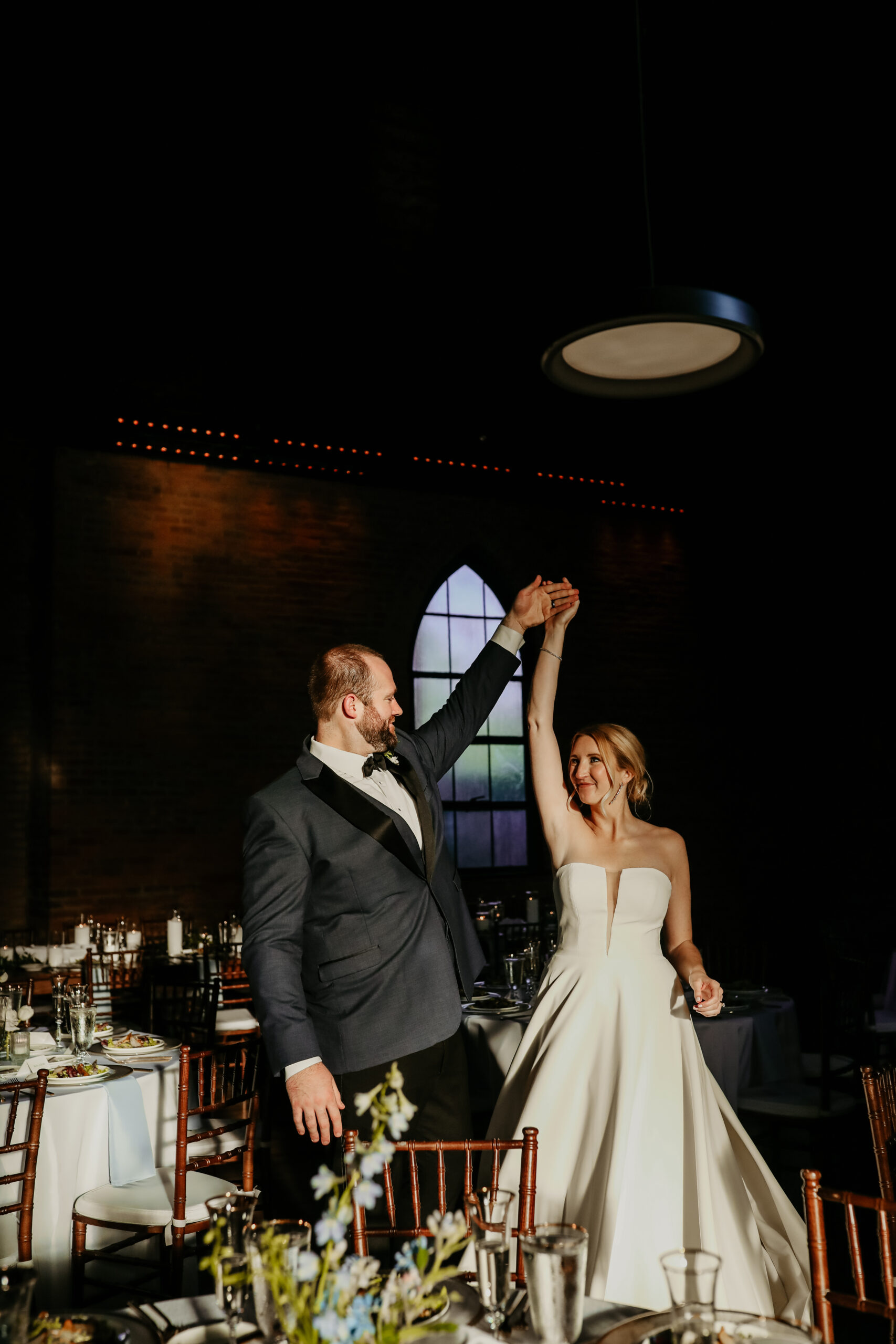 Newlyweds entering their reception hand raised in a brick loft wedding venue