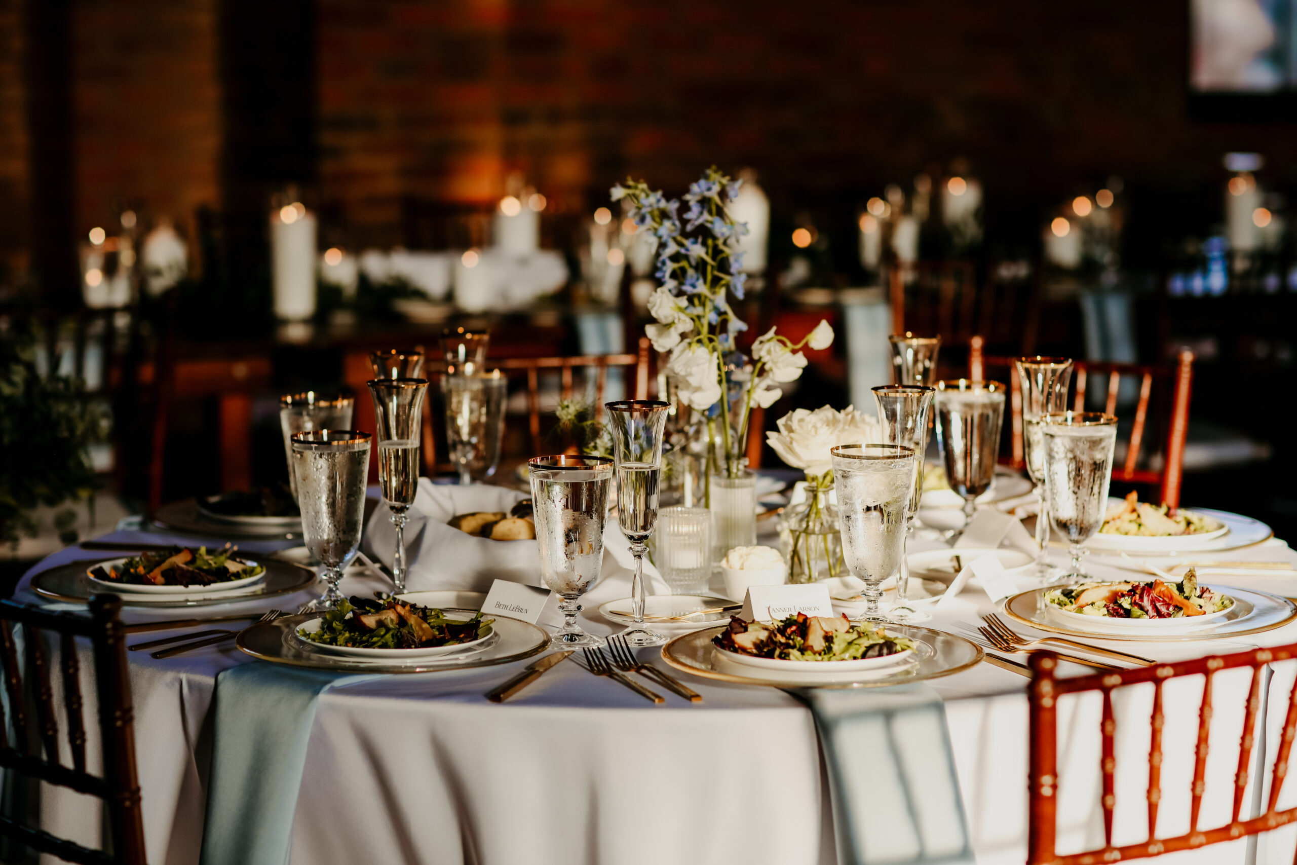 Round wedding reception table set with gold rimmed glassware and place cards
