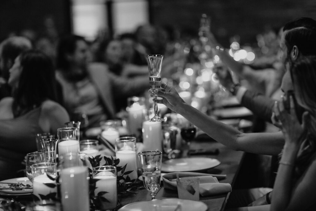 toast - CM Event Design Guests raising glasses for a toast during a candlelit wedding reception