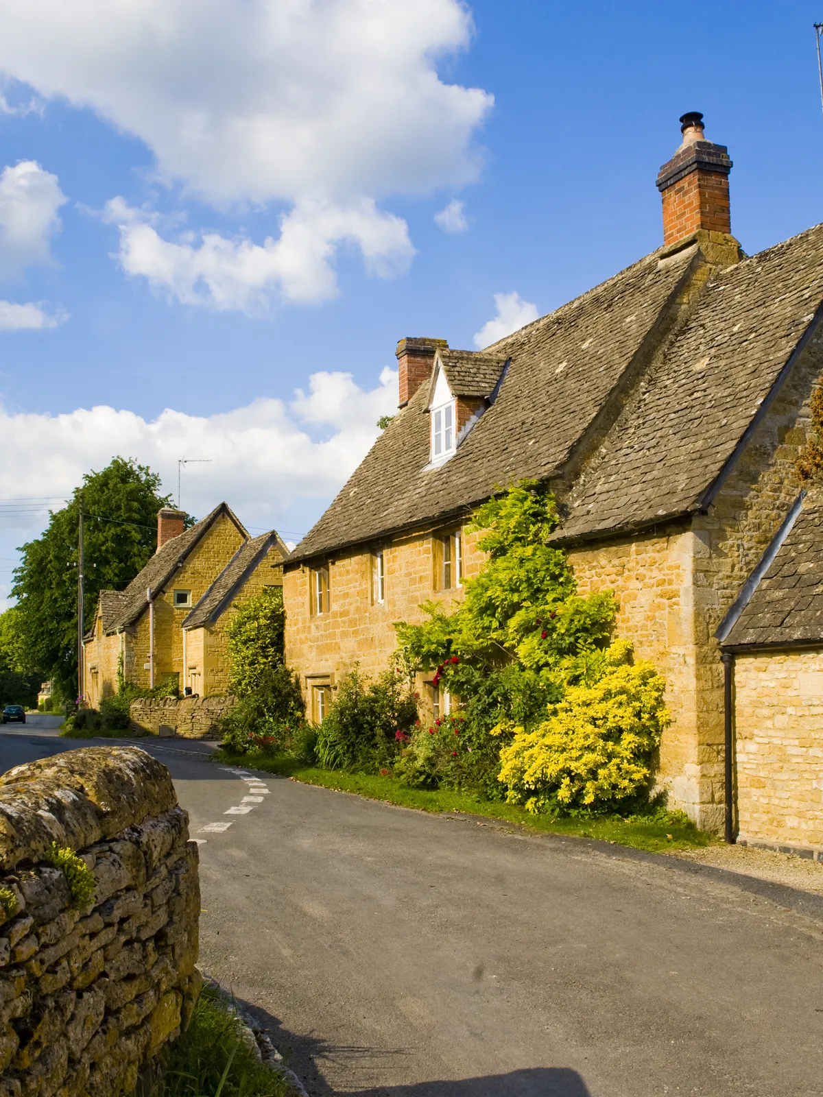 Honey-colored stone cottages along a village lane in the Cotswolds, England